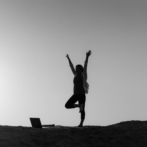 Silhouette of a person stretching during sunrise at home.